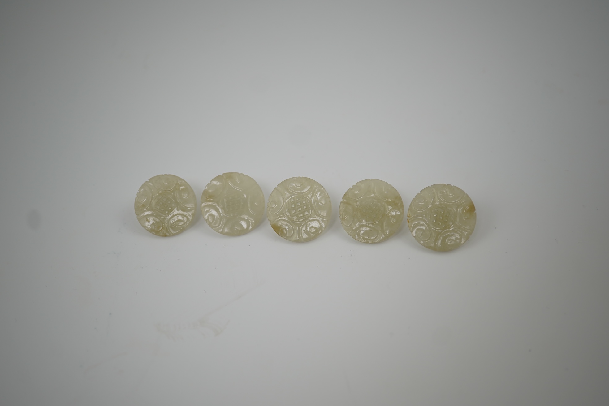 A set of five Chinese pale celadon jade robe buttons, 19th century